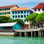 **

A vibrant coastal scene in Penang, Malaysia. Focus on a blend of modern and traditional elements: colourful heritage buildings alongside green infrastructure (coastal parks, possibly a glimpse of artificial reefs).  Show tourists and locals enjoying the area.  Incorporate subtle elements hinting at sustainable practices, like solar panels on rooftops or electric vehicles.  The overall feel should be lively and prosperous, highlighting the success of balancing tourism with environmental preservation.

**